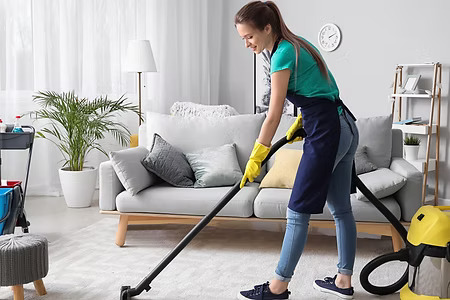 Professional cleaner steam cleaning carpet in modern living room
