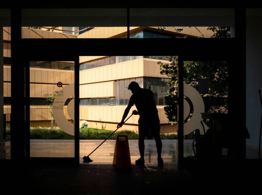 Professional cleaner mopping high-traffic floor area with caution sign in view.