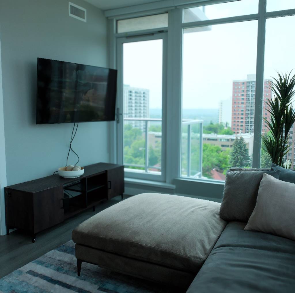 Modern living room with clean carpet and floor-to-ceiling windows in a high-rise apartment