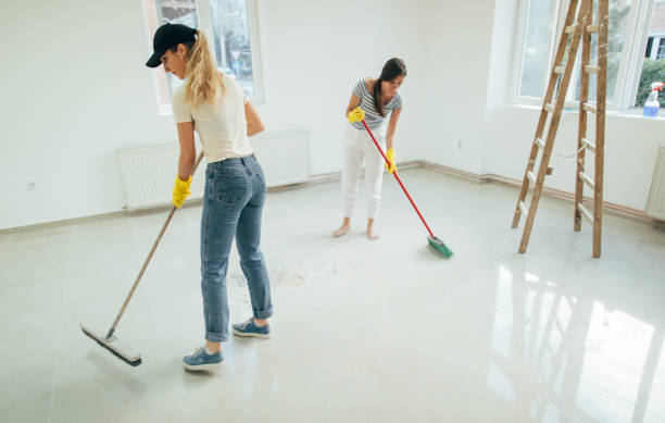 Two professional cleaners scrubbing and mopping a residential floor during a deep clean.
