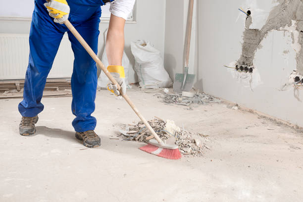 Worker sweeping concrete dust and rubble at renovation site